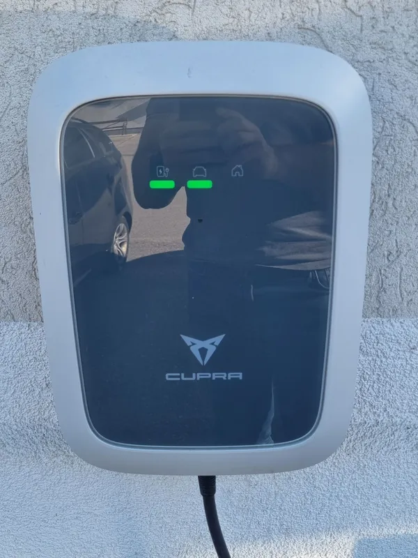 Wallbox des Autoherstellers an der Hauswand mit Ladekabel und Statusanzeige